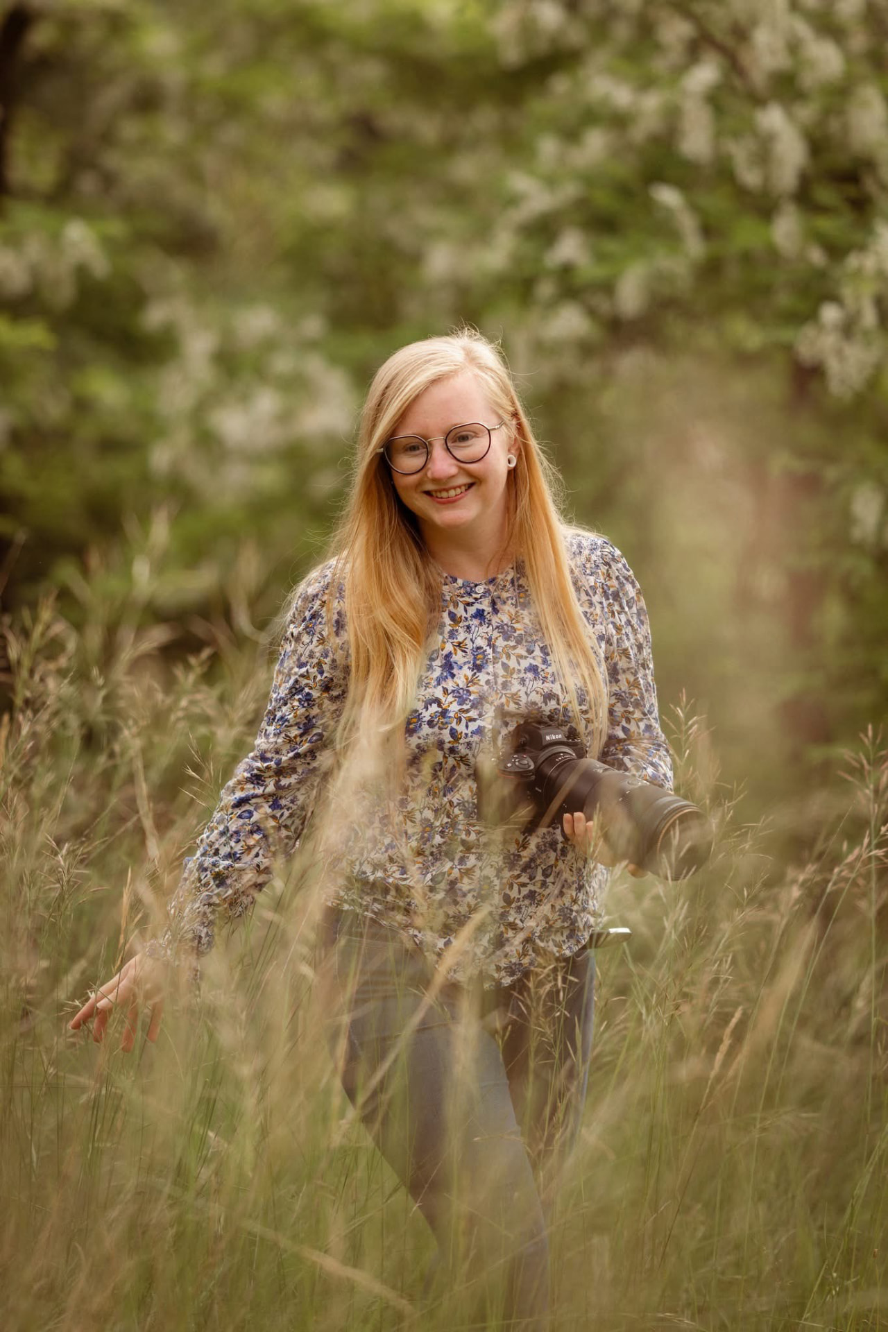 Dorine Routier, photographe, dans les hautes herbes avec son appareil photo